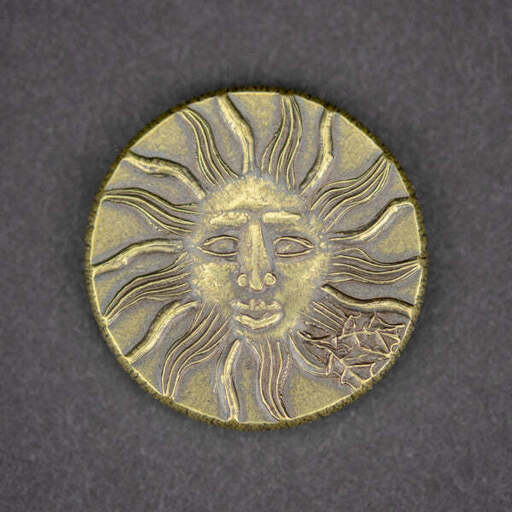 A gold-looking coin eith sun personification (face), against grey fabric backdrop.