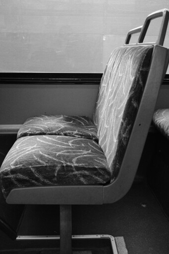 A black and white photo of a bus seat from a side angle 