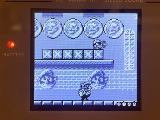 Wario standing below a platform with gold coins. 